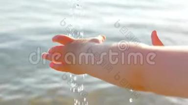 婴儿手抓水<strong>滴</strong>在海景背景上。 幼儿用手拿着装有海水的水<strong>滴</strong>玩